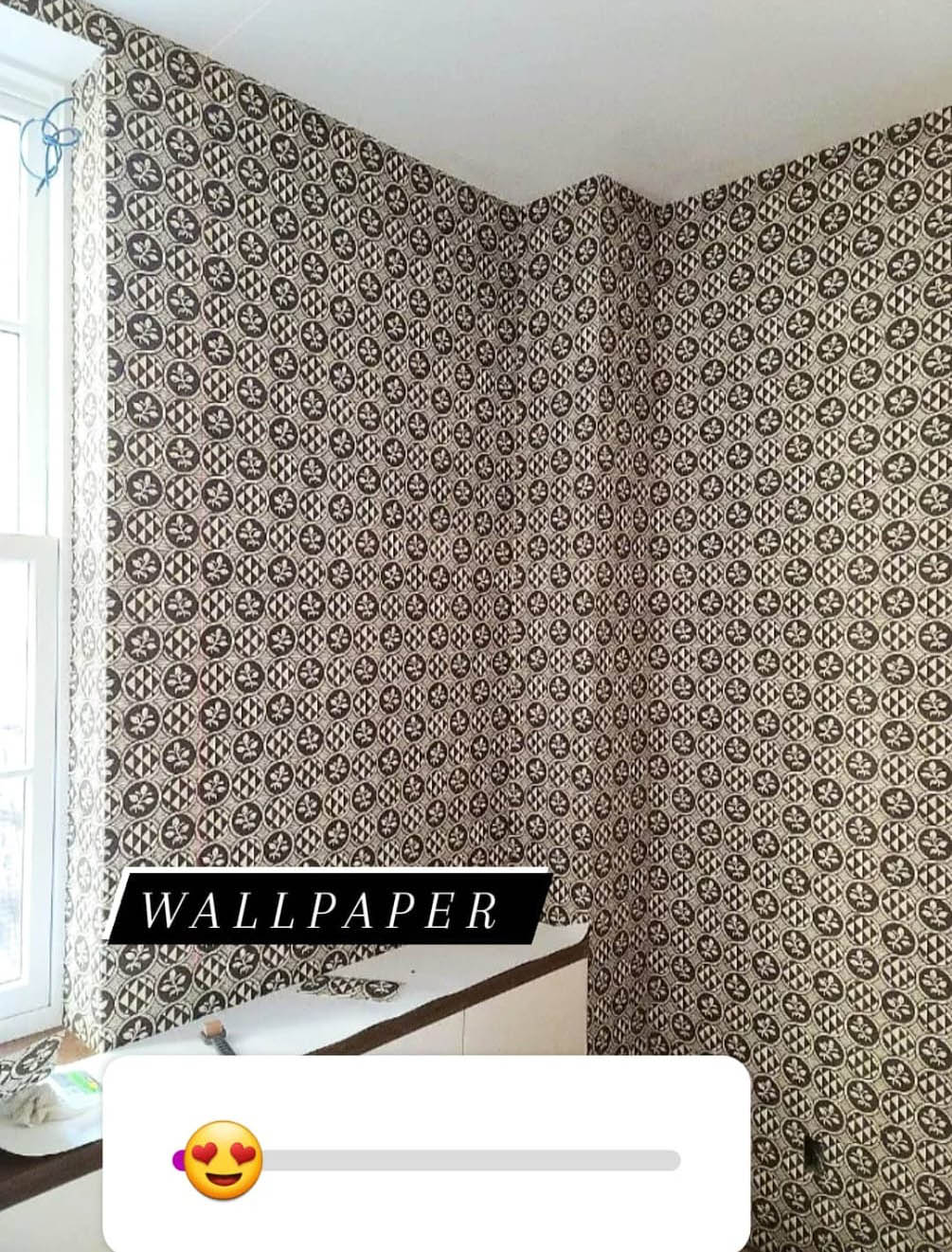 Room corner with black and white patterned wallpaper featuring floral and geometric motifs.